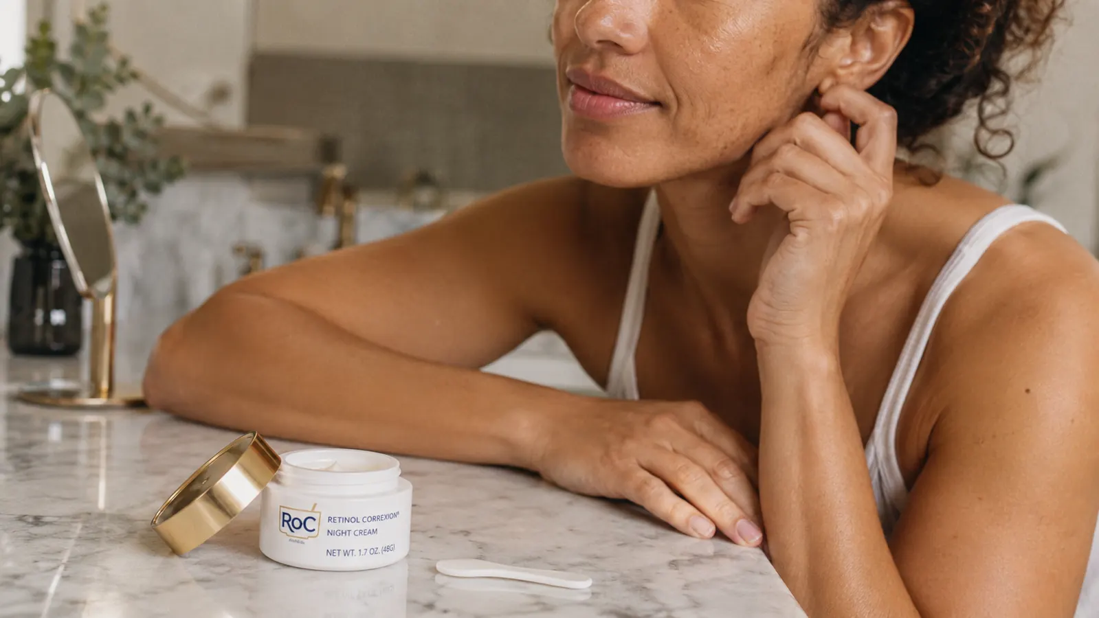 RoC Retinol Correxion night cream jar on a marble surface with a few skincare essentials